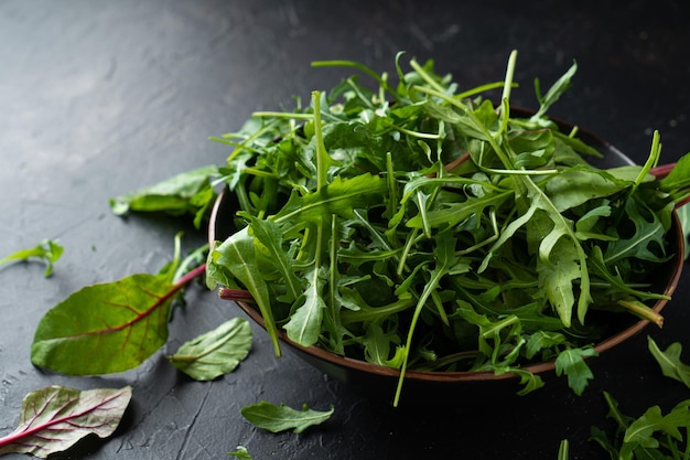 Mélanger les feuilles de salade. Roquette, laitue, épinards dans un bol noir