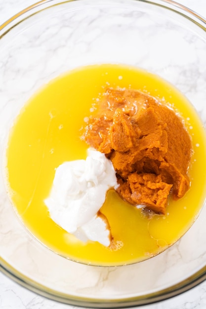 Mélanger les ingrédients dans un grand bol en verre pour cuire un gâteau bundt à la citrouille au chocolat avec glaçage au caramel