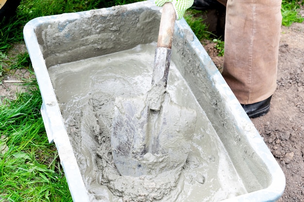 Mélanger le mortier de béton de coulis de ciment en remuant avec une pelle Rénovation du bâtiment Pose des fondations