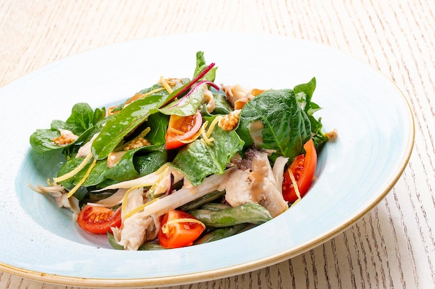 Mélanger la salade avec du poulet et des tomates sur fond clair