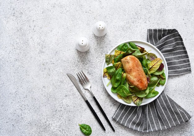 Mélanger la salade avec la poitrine de poulet sur une assiette sur une surface en béton