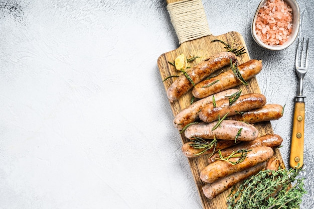 Mélanger Les Saucisses Grillées Aux Herbes Sur Une Planche à Découper. Fond Blanc. Vue De Dessus. Copiez L'espace.