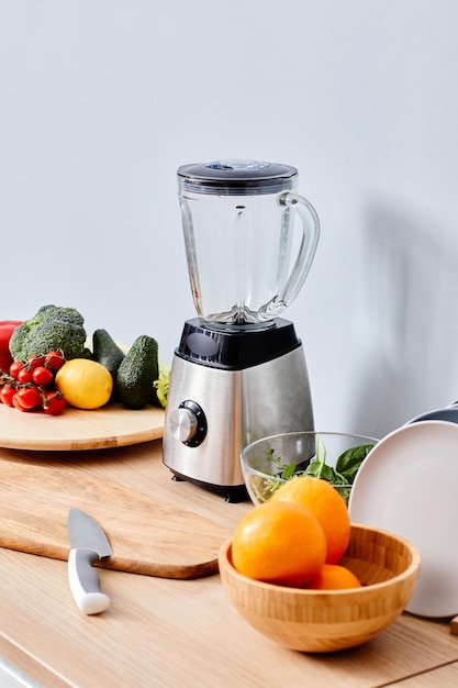 Mélangeur électrique pour faire du jus frais debout sur une table avec des fruits et légumes frais