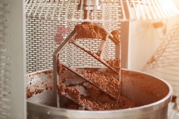 Mélangeur industriel à pâte brune. Énorme lame de mélangeur industriel. Ingrédient pour les bonbons au chocolat. Première étape de fabrication.