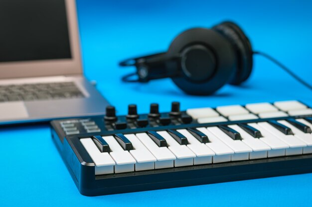 Mélangeur de musique et casque et ordinateur portable sur une surface bleue. Équipement pour enregistrer des morceaux de musique.
