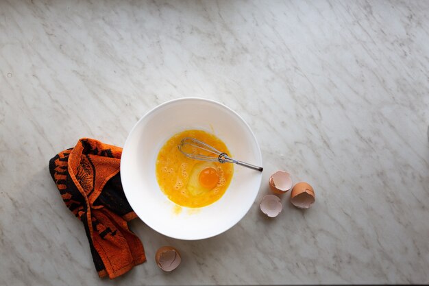 Mélangez les œufs pour l'omelette ou la cuisson du pain aux bananes sur une table lumineuse près de la fenêtre