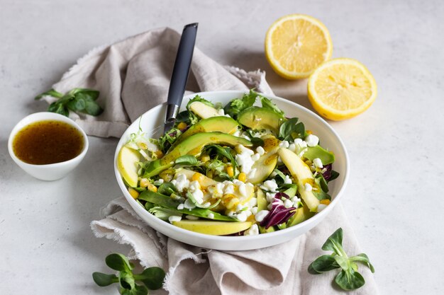 Mélangez la salade avec du maïs, de la pomme, de l'avocat et du fromage cottage