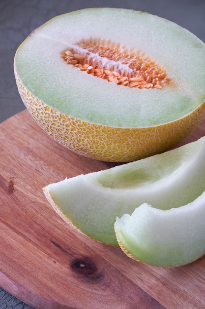 Melon cantaloup tranché sur planche de bois sur dark