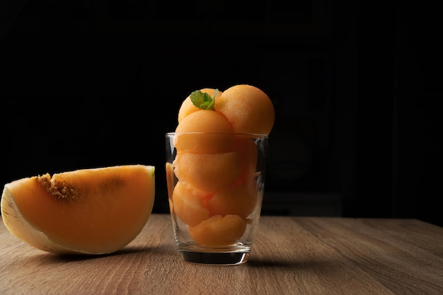 Photo melon à chair jaune a été versé dans une boule ronde comme de la crème glacée mettre dans un verre transparent