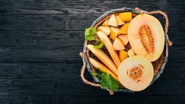 Melon dans une boîte en bois Tranché en morceaux de melon Sur un fond en bois Espace libre pour le texte Vue de dessus