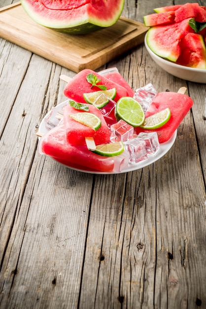 Melon d'eau sucré d'été et sucettes glacées au citron vert avec pastèque en tranches et menthe