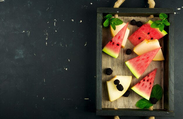 Melon, pastèque, mûres et menthe sur une table en bois