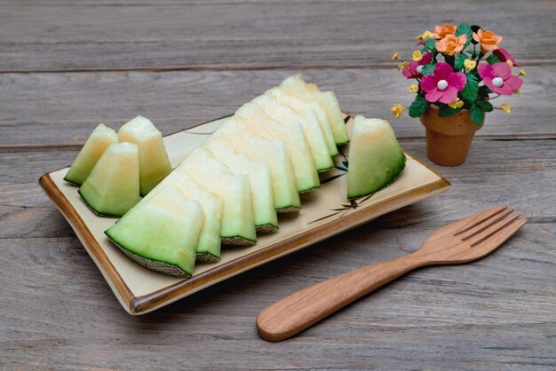 melon tranché sur un plat avec une fourchette en bois sur une table en bois