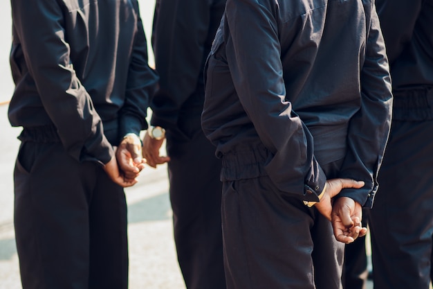 Des membres des forces de police veillent sur la vue arrière de la construction, mains sombres. afro-américains