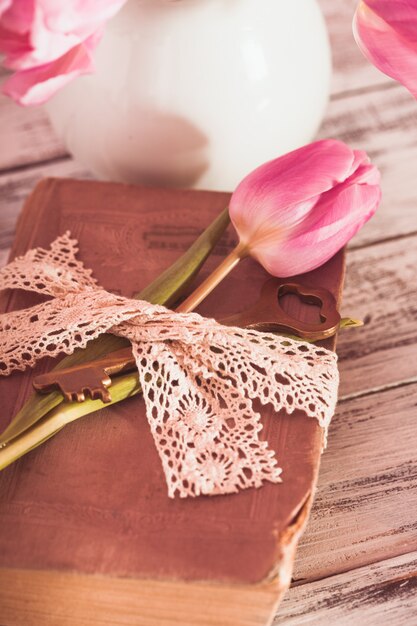 Memo nature morte avec livre, clé, dentelle vintage et tulipes roses