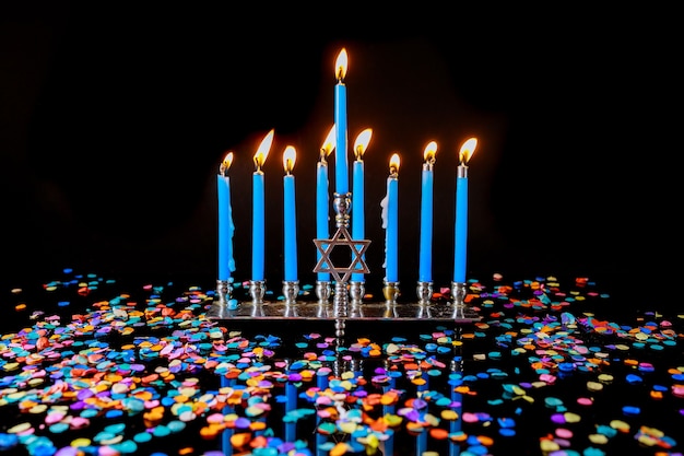 Menorah avec des bougies allumées bleues et des confettis pour la fête juive de Hanoukka.