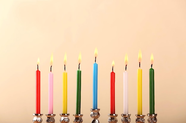 Menorah avec des bougies colorées pour Hanukkah sur fond clair se bouchent