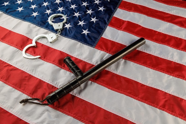 Menottes en métal argenté et matraque de police sur le drapeau américain sur une surface plane