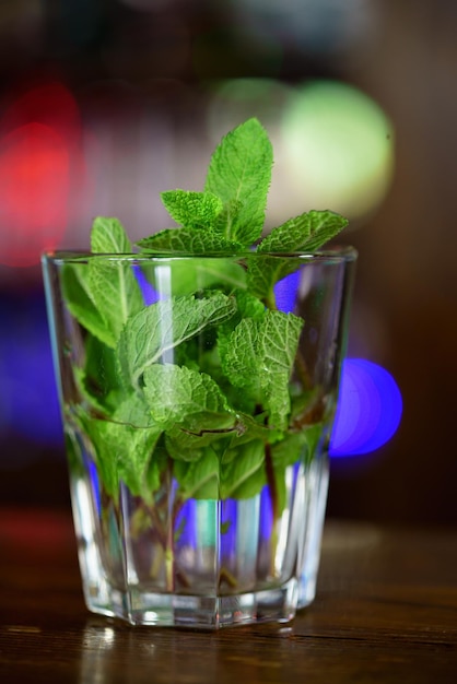 la menthe fraîche est dans un verre pour la cuisson du mojito sur la table du café. Fermer