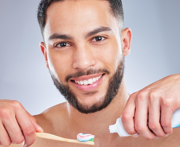 Menthe fraîche est toujours la meilleure prise de vue en studio d'un beau jeune homme se brosser les dents sur un fond gris