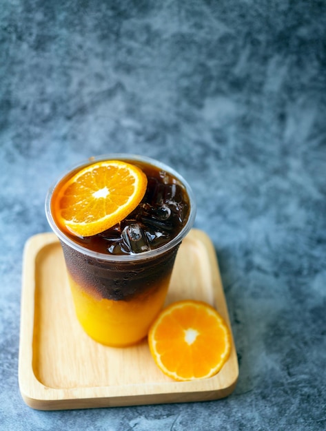 Menu de boissons au café glacé Orange Americano fusion avec des fruits orange frais mélangés dans une tasse en plastique