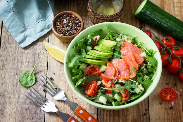 Menu diététique Salade saine avec quinoa roquette Tomates Saumon et avocat sur table rustique