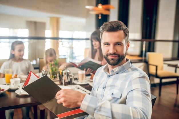 Avec menu. Jeune homme tenant un menu et choisir quoi commander