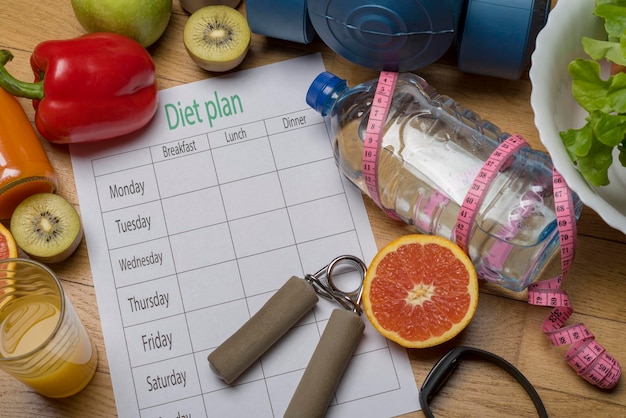 Photo menu de plan de régime ou programme d'haltères d'eau de roulette et aliments diététiques avec des fruits frais sur un plancher en bois