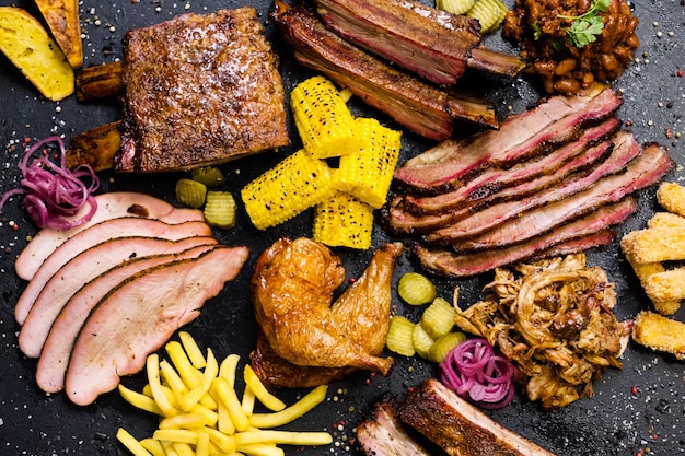 Menu steakhouse. Vue de dessus d'un assortiment de viandes fumées en tranches, de frites et de plats de légumes.