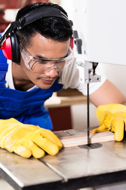 Menuisier asiatique sur scie à bois en atelier