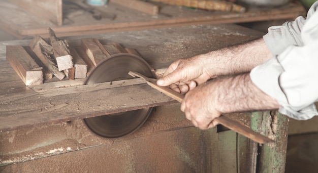 Menuisier coupant un morceau de bois avec une machine de menuiserie.