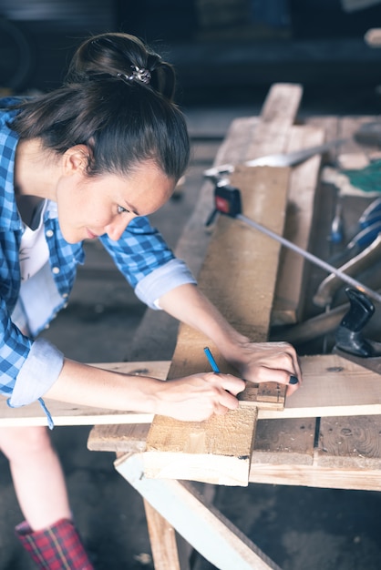 Menuisier dans un atelier à domicile s'appuie sur une planche de bois ligne de coupe au crayon