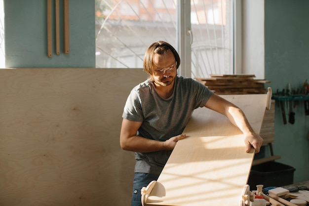 Un menuisier fabrique un kit d'escalade Montessori pour les enfants dans son atelier