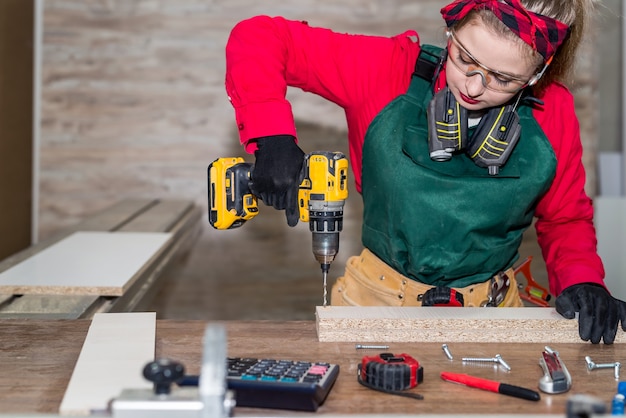 Menuisier de femme faisant le trou dans la planche de bois