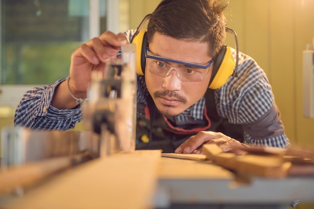 Menuisier travaillant avec de l'équipement sur une table en bois dans un atelier de menuiserie