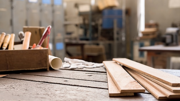 Menuisier travaillant avec des équipements sur une table en bois dans un atelier de menuiserie.