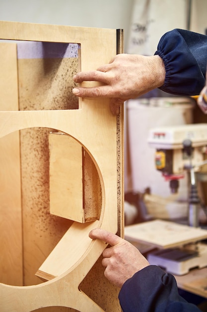 Le menuisier travaille avec des pièces en bois en collant des éléments de meulage dans l'atelier