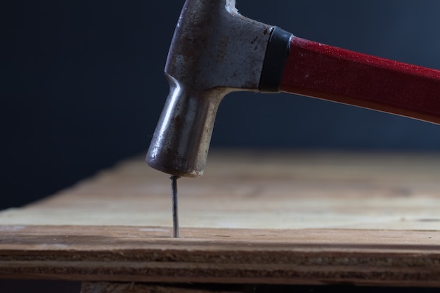 Photo le menuisier utilise un marteau pour frapper l'ongle sur le plancher en bois