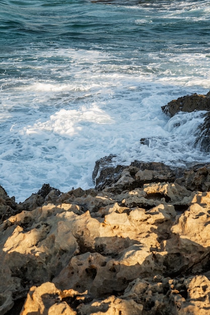 mer bleue bouillonnante avec des vagues mousseuses sur un rivage rocheux. Plage sauvage, belle nature.