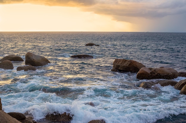 Mer bouillante orageuse avec un rivage rocheux au coucher du soleil paysage dramatique maritime