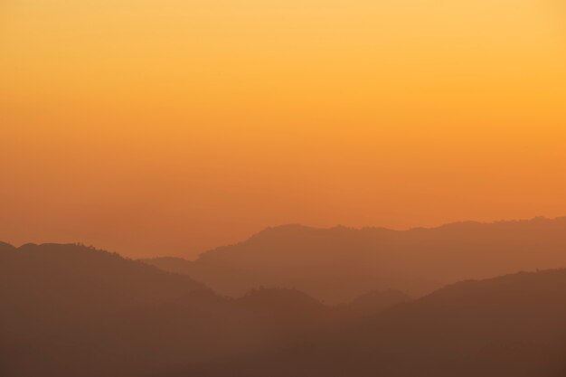 Mer de brouillard et silhouette de montagne pendant le lever du soleil