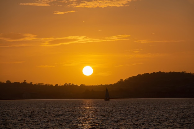 Mer calme avec ciel coucher de soleil et soleil à travers les nuages sur Voilier dans la mer