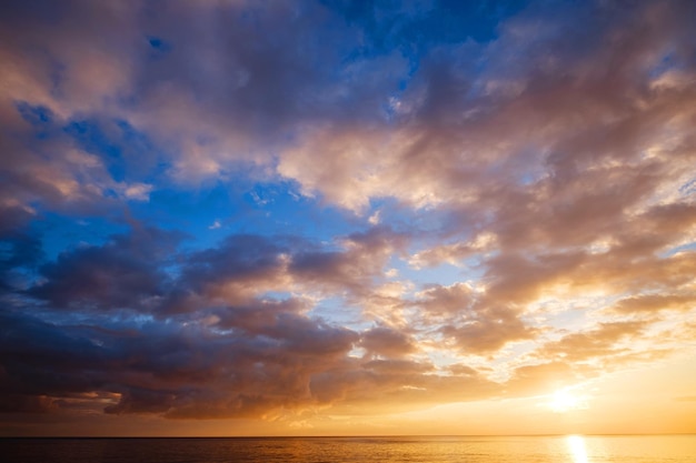 Mer calme avec ciel coucher de soleil et soleil à travers les nuages