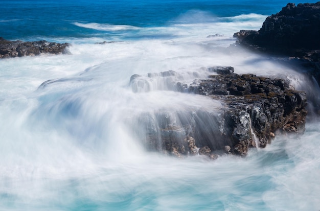 La mer déchaînée coule sur les rochers de lave sur la ligne de rivage