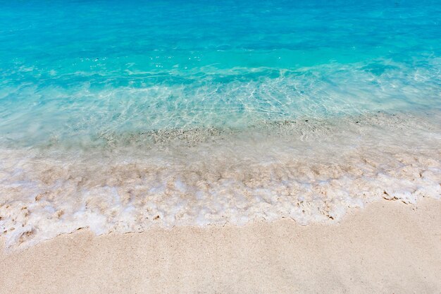 Photo la mer est turquoise avec des éclaboussures sur la plage de sable.