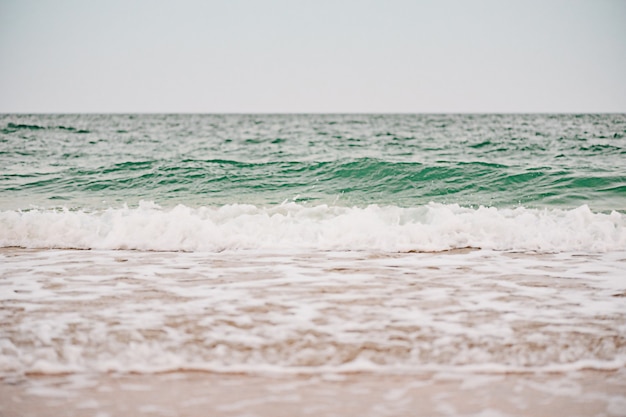 Mer par temps chaud et nuageux avec ciel bleu. Vagues de la mer et sable en été.