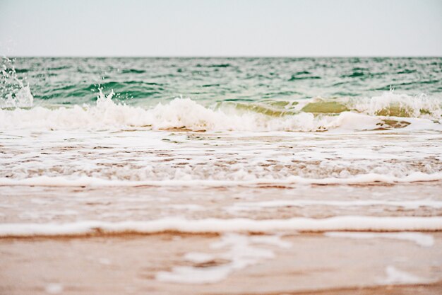 Mer par temps chaud et nuageux avec ciel bleu. Vagues de la mer et sable en été.