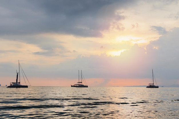 Mer avec des silhouettes de divers bateaux contre un ciel coucher de soleil