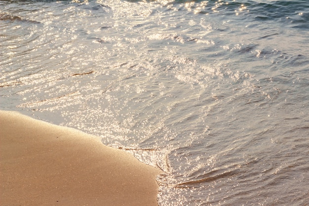 La mer tombe sur la plage, la lumière tombe à la surface de la mer