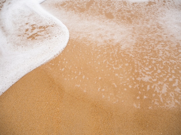 Mer de vague de mousse blanche sur fond de plage de sable à la côte se bouchent. magnifique paysage naturel de l'océan de l'île de Phuket en plein air. mise à plat avec espace libre. concept de voyage de vacances d'été touristique tropical.